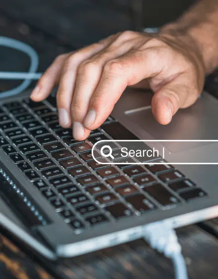 Close-up of hand typing on laptop with search bar overlay, symbolizing SEO optimization India